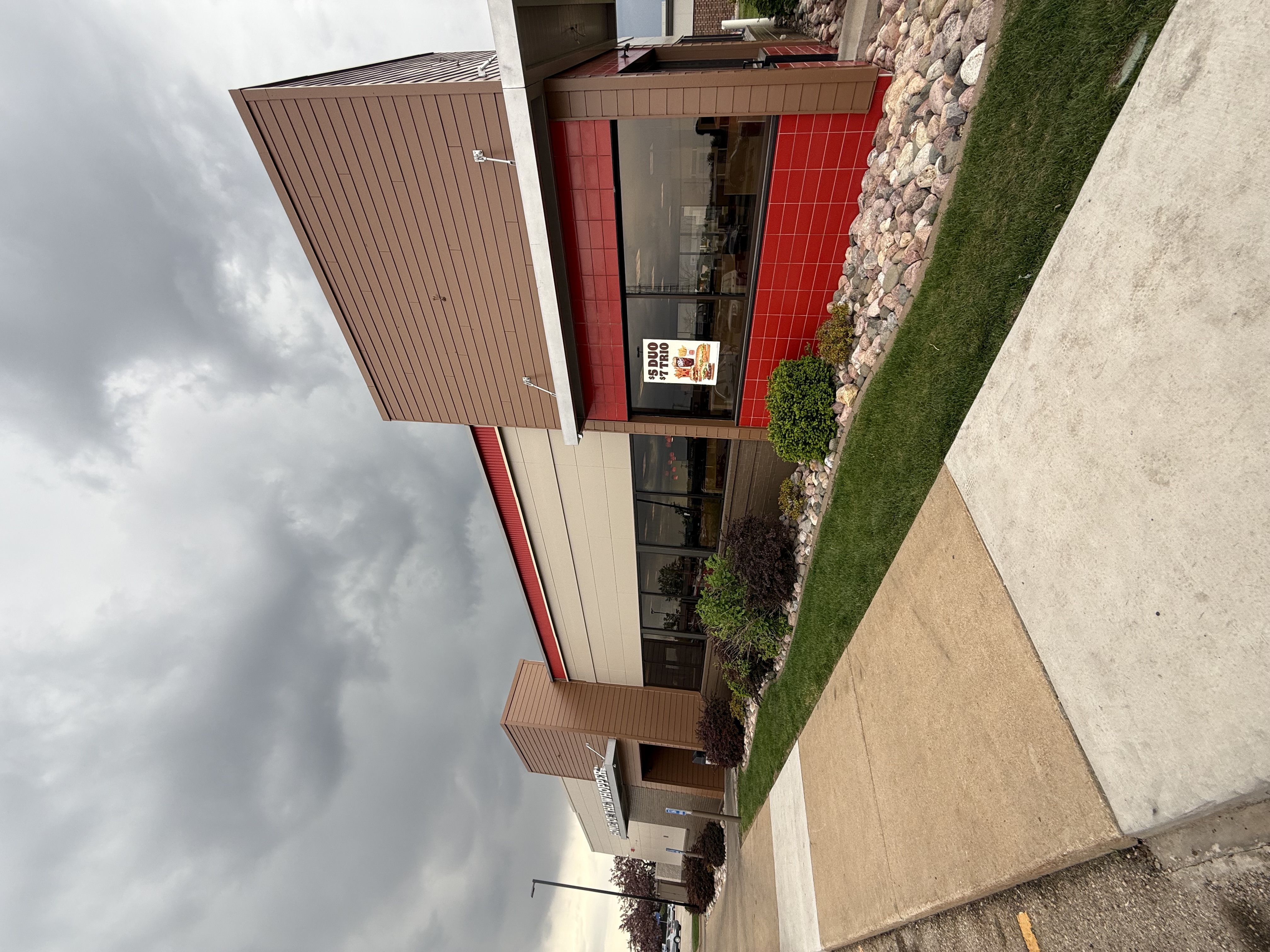 Completed Burger King exterior with tan siding, red accent panels, and stone veneer detail painted by Maverick Painting
